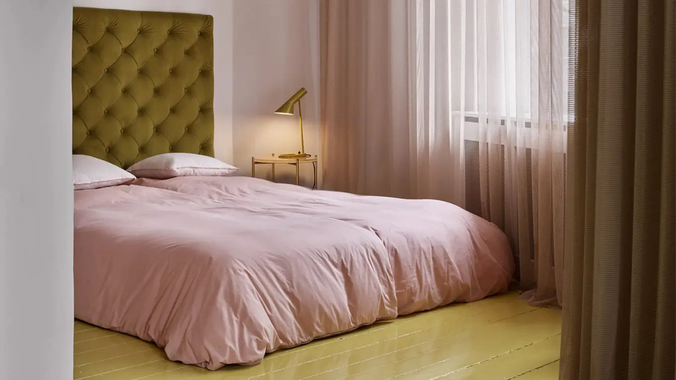 louis poulsen AJ Tischlampe auf einem nachttisch neben einem bett mit rosa bettwäsche