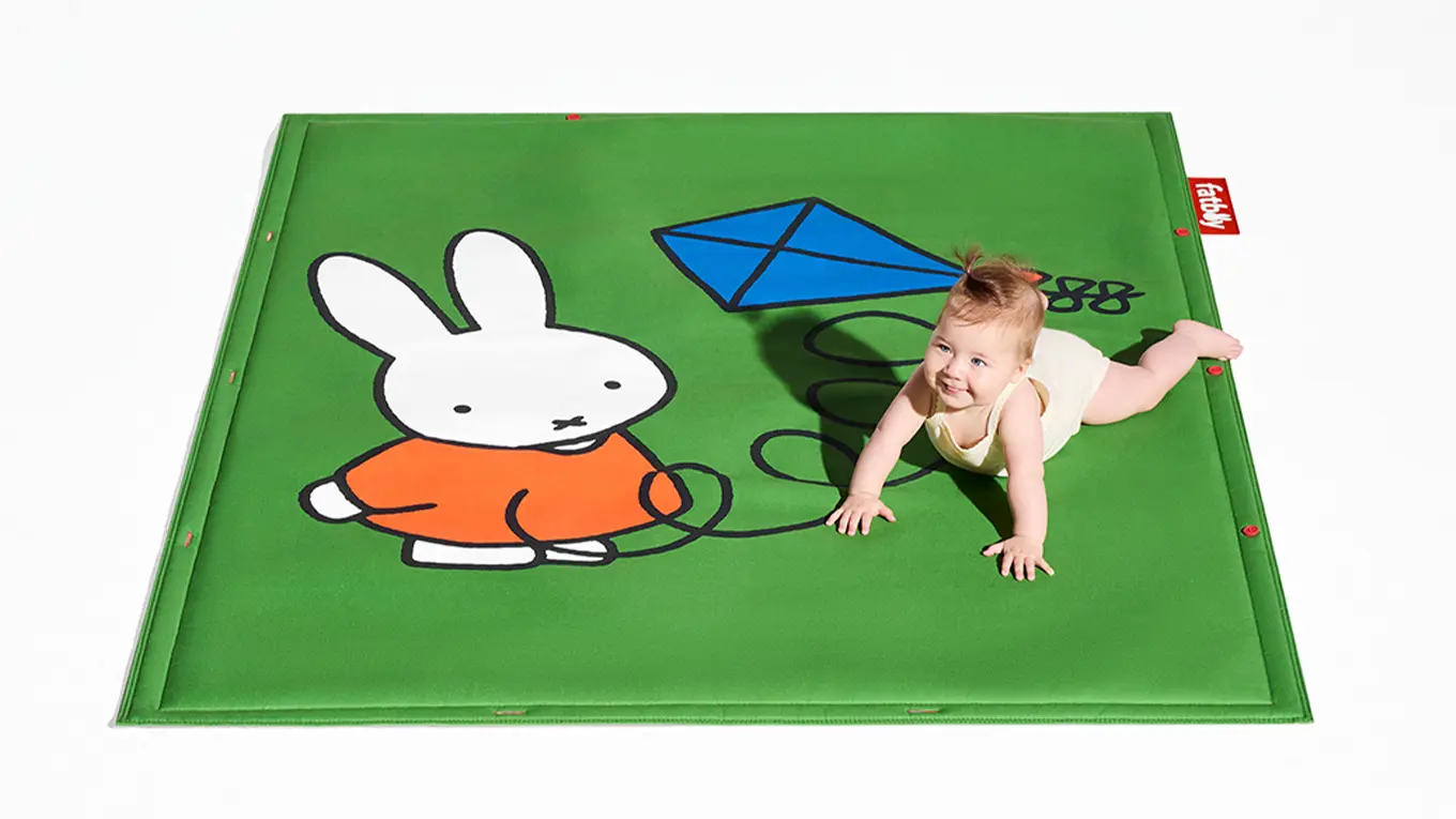Baby auf einem Fatboy Miffy Teppich in grün