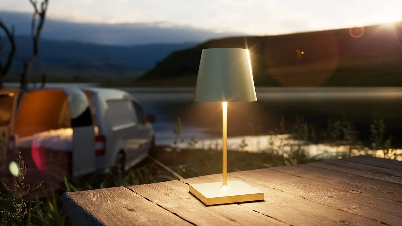 Sigor Nuindie Tischlampe auf einem gartentisch mit camper im hintergrund